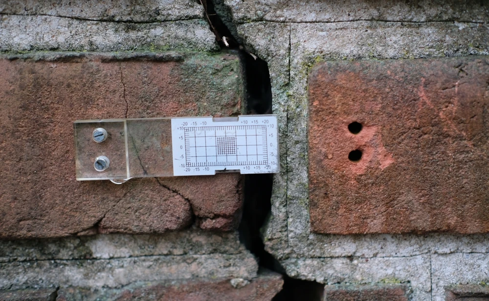 Dispositif gradué de suivi fixé sur un mur en briques fissuré
