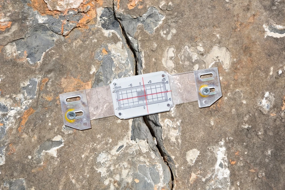 Suivi des fissures — Nos Murs Jauge graduée posée sur une fissure de façade à l’enduit dégradé