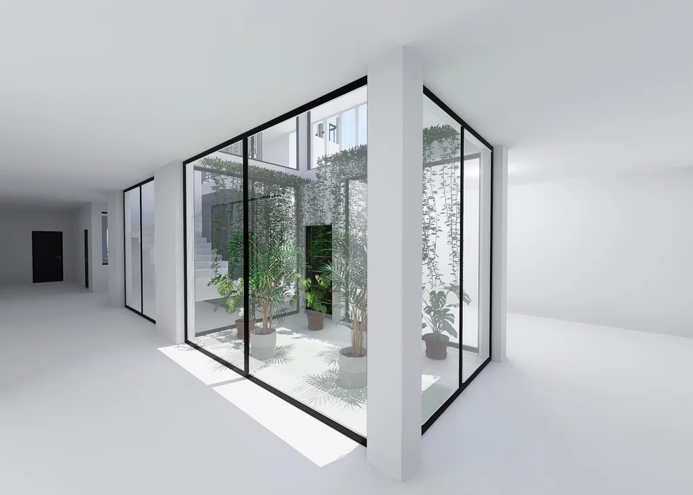 Jonction conservée autour d’un patio — Nos Murs Élément vertical blanc à la jonction de deux parois vitrées autour d’un patio planté