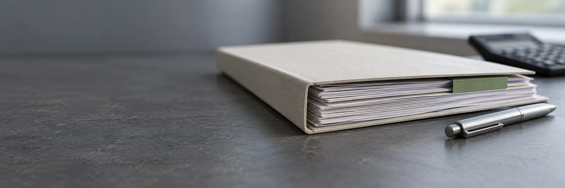 Dossier d’étude et stylo, avec une calculatrice en arrière-plan